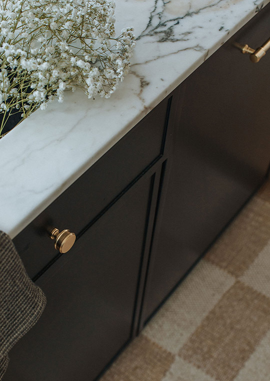 J. Reiko Design + Co. - Modern Colonial Interior Design - 02 Close-up of black cabinetry with marble countertop, brass pulls, and soft floral styling.