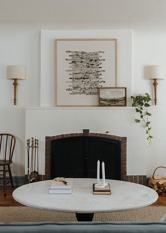 J. Reiko Design + Co. - Modern Colonial Interior Design - 04 Styled living room fireplace with symmetrical sconces, layered artwork, and round marble coffee table.