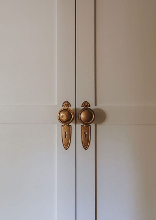 J. Reiko Design + Co. - Modern Colonial Interior Design - 05 Antique-style brass knobs on painted double doors, highlighting classic colonial hardware.
