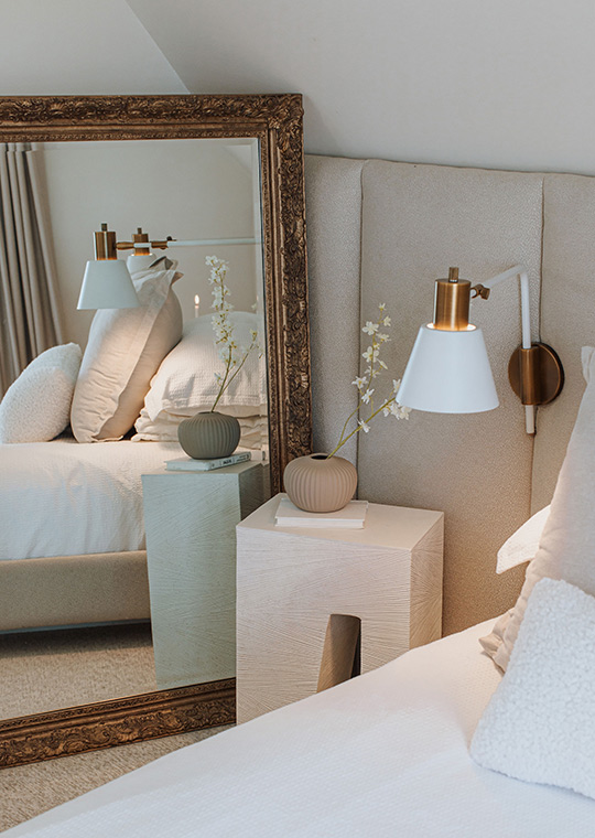J. Reiko Design + Co. - Modern Colonial Interior Design - 07 Bedroom vignette with ornate vintage mirror, sculptural nightstand, and brass-and-white sconce.
