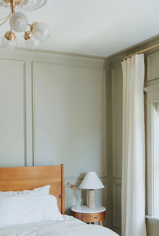 J. Reiko Design + Co. - Modern Colonial Interior Design - 10 Paneled bedroom with natural wood bed, layered white bedding, and vintage-inspired chandelier.