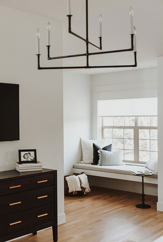J. Reiko Design + Co. - Modern Colonial Interior Design - 13 Bright room with black linear chandelier, built-in window seat, and dark wood dresser.