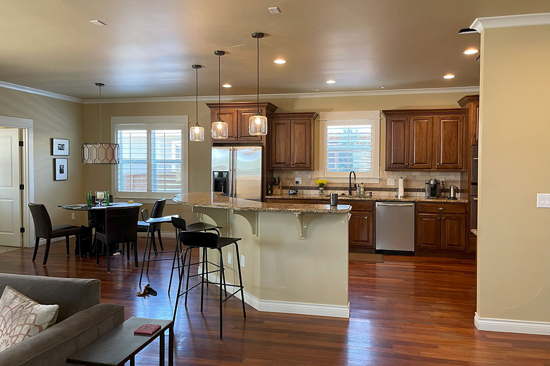 Before kitchen with traditional wood cabinetry, granite peninsula, and mixed pendant lighting.