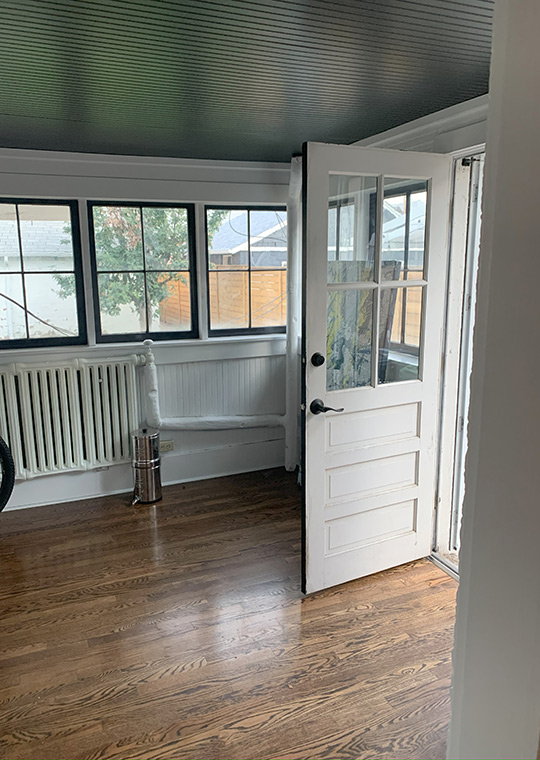 Before sunroom/entry space with dark ceiling, hardwood floors, and minimal furnishings.