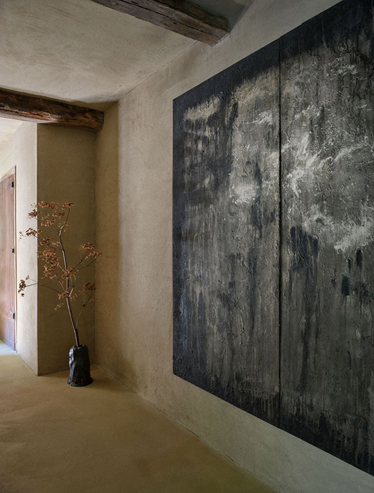 J. Reiko Design + Co. - Quiet Luxury Living Room Ideas - 03 Plaster hallway with oversized abstract artwork, exposed wood beams, and organic vase styling.
