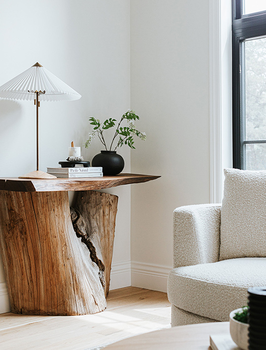 J. Reiko Design + Co. - Quiet Luxury Living Room Ideas - 05 Organic modern living room corner with sculptural natural wood side table, pleated lamp, and textured boucle chair.
